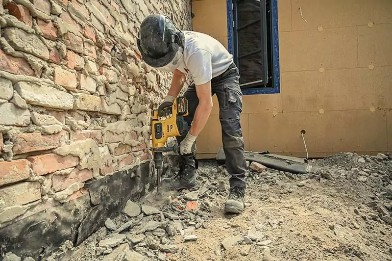 Arbeiter vom Bauunternehmen Nordwerk bei der Mauerentkernung während Abbrucharbeiten mit Bohrhammer auf einer Baustelle -Rügen.