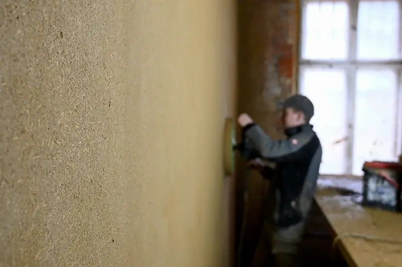 Lehmputz-Arbeiten im Innenbereich auf Rügen – Handwerker glättet ökologisch verputzte Wand für ein gesundes Raumklima