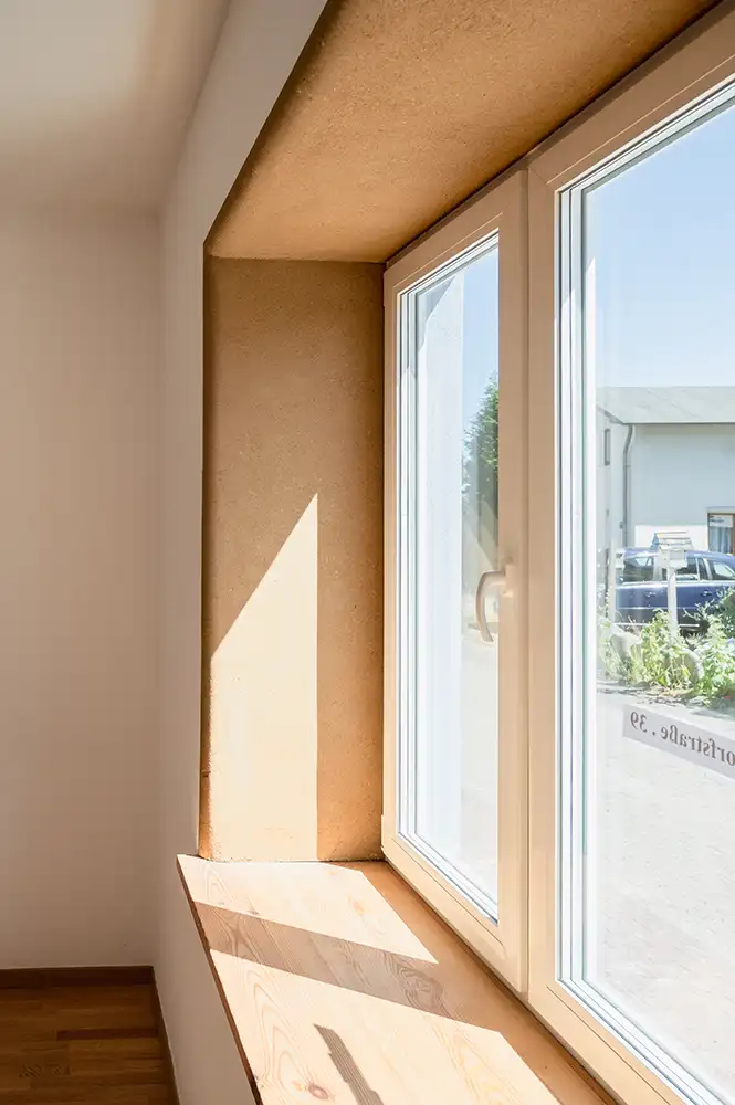 Lehmputz in einer Fenster-Leibung in Kombination mit Kalkputz an den Wänden - Sonne scheint durchs fenster auf den Lehmputz