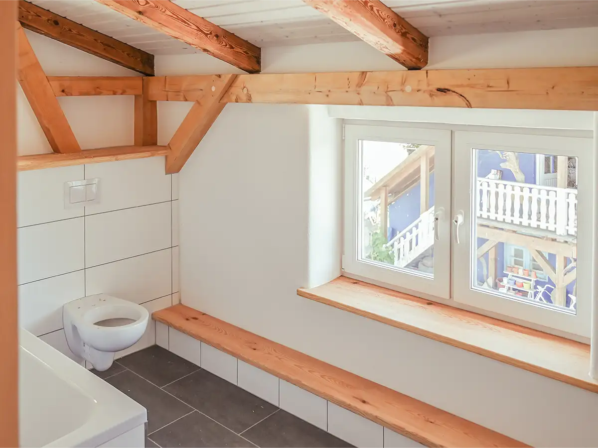 Saniertes Badezimmer mit neuer Toilette und neuer Badewanne neu gefliest mit Anthrazitfarbenden Fliesen