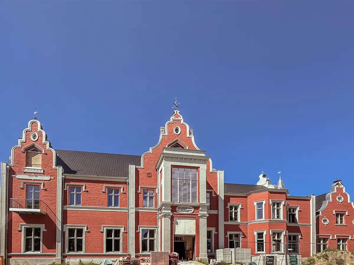 NordWerk – Sanierung historischer Gebäude und Fassaden auf Rügen Historisches Gebäude mit roter Fassade während der Sanierung durch NordWerk Rügen