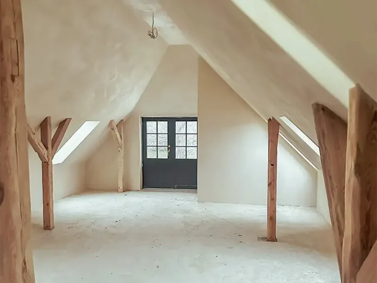 Saniertes Dachgeschoss mit sichtbaren Holzbalken und neuen Putzflächen auf Rügen