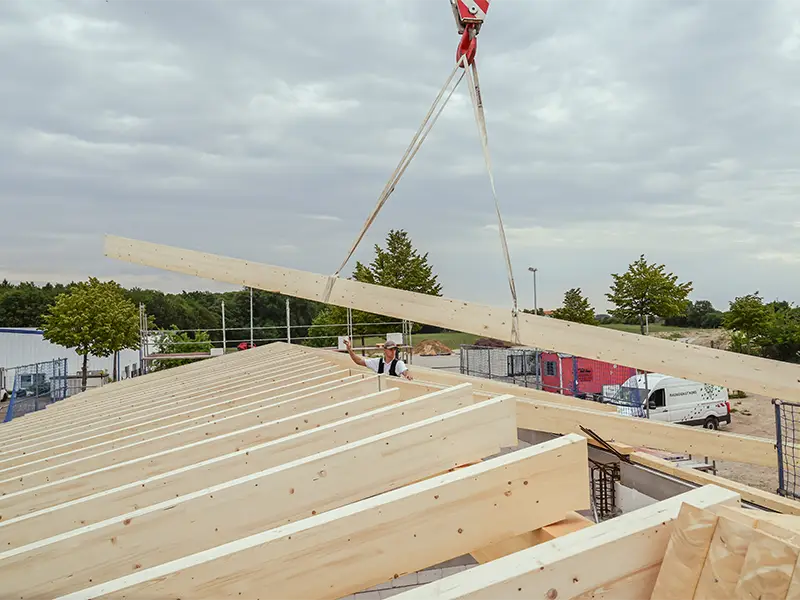 Holzbalken werden per Kran auf eine Dachkonstruktion gesetzt – Zimmereiarbeiten von NordWerk auf Rügen